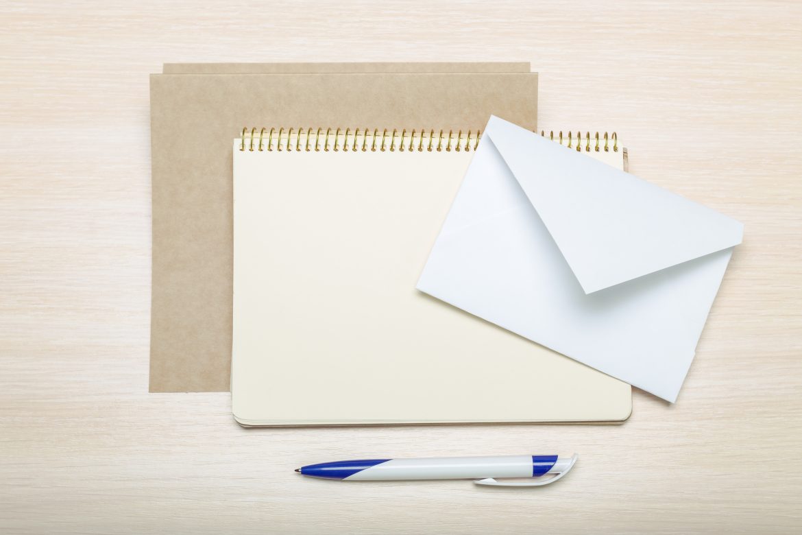 foto de um envelope branco, caderno e caneta
